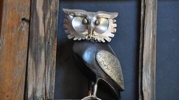 A metal owl sculpture with intricate designs, placed in a wooden frame.