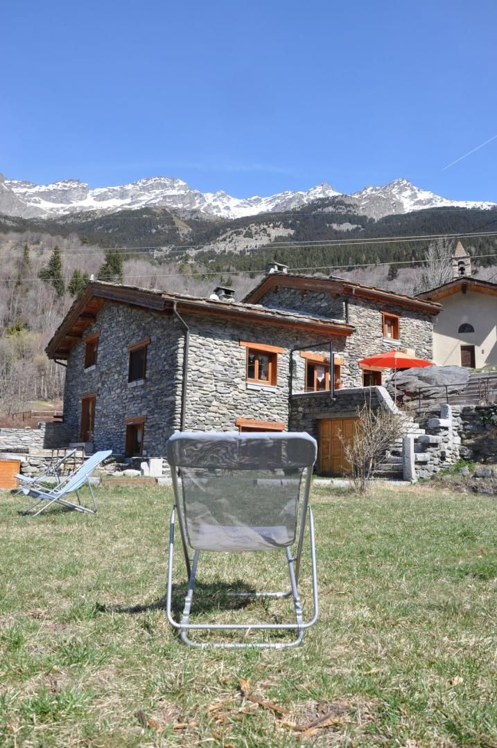 Una casa in pietra con vista chiara su montagne innevate sullo sfondo.