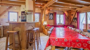 Una cabaña de madera con cocina, comedor y una cama grande.