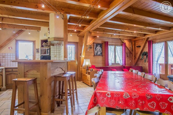 A wooden cabin with a kitchen, dining area, and a large bed.