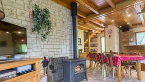 Un interior rústico con pared de piedra, chimenea, muebles de madera y televisor.