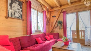 Una cabaña de madera acogedora, con un sofá rojo, un aparador de madera y un cuadro en la pared.
