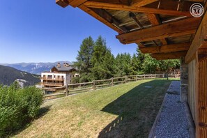 A wooden cabin with a balcony overlooking a mountainous landscape.