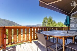 A wooden deck with a round table and chairs, overlooking a mountainous landscape. - Chalet LE Dahu - Peisey-nancroix (PEISEY NANCROIX)