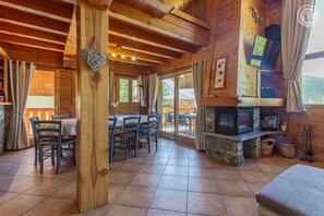 A wooden interior with a dining area, stone fireplace, and a television. - Chalet LE Dahu - Peisey-nancroix (PEISEY NANCROIX)
