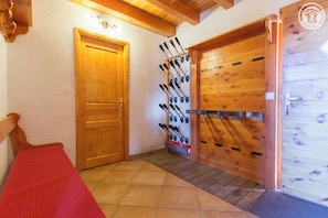 A wooden door with a bench, a wall-mounted rack of skis, and a wooden wall with a logo. - Chalet LE Dahu - Peisey-nancroix (PEISEY NANCROIX)