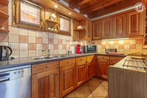 A kitchen with wooden cabinets, a stainless steel dishwasher, a microwave, and a coffee maker. - Chalet LE Dahu - Peisey-nancroix (PEISEY NANCROIX)