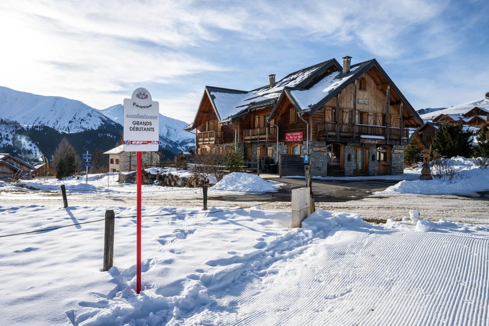 A wooden chalet with a sign indicating it's a ski resort.
