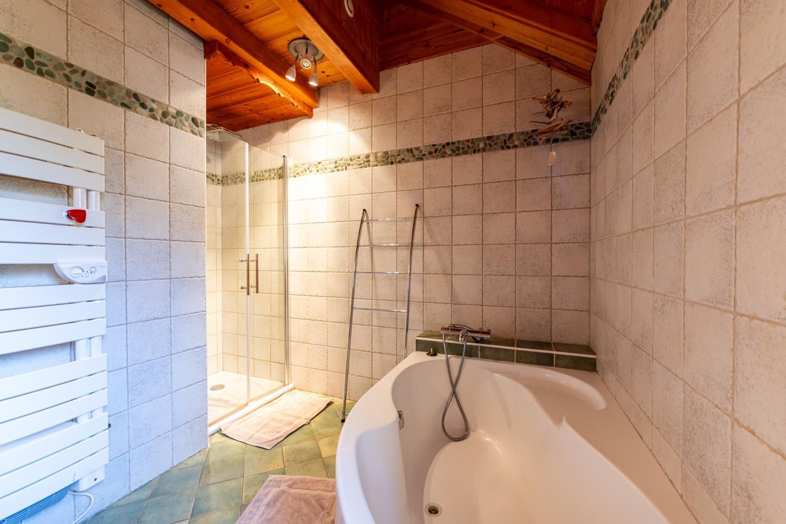 Een badkamer met een bad, een douche en een douchecabine met glazen wanden.