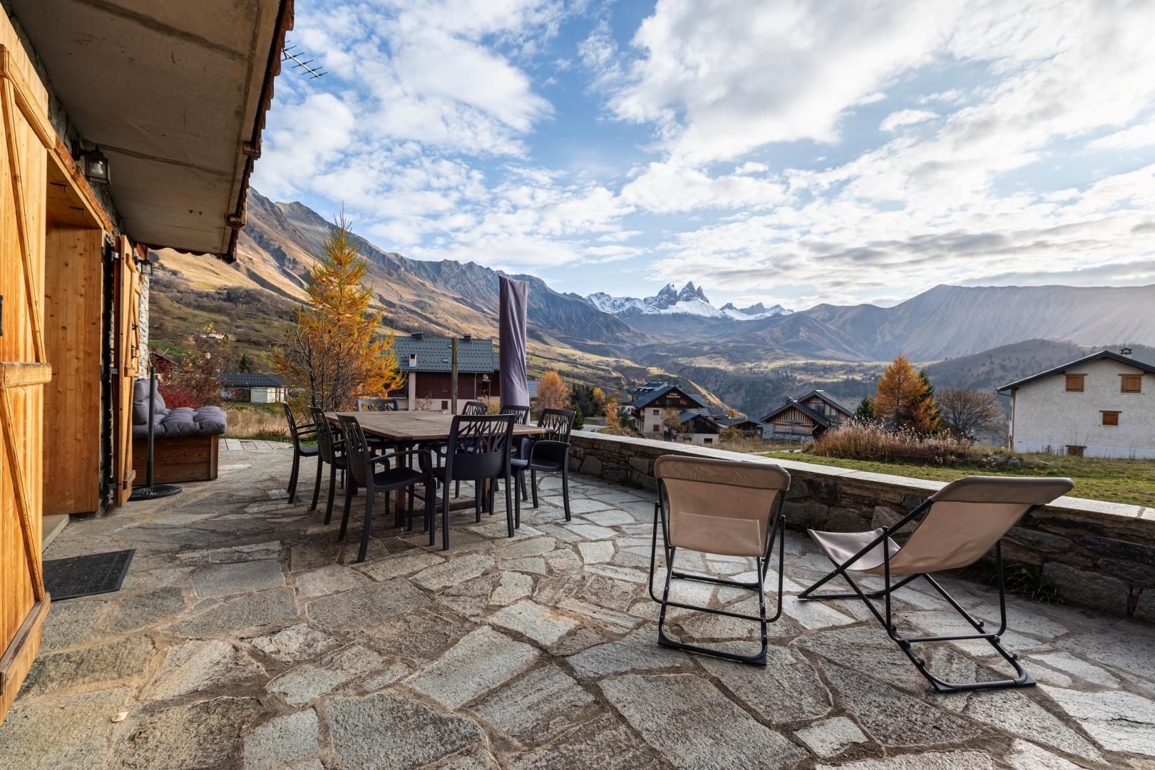 Un espace extérieur aménagé avec un sol en pierre, du mobilier en bois et une vue sur les montagnes.