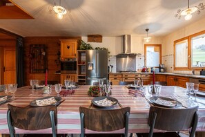 Una cocina moderna con electrodomésticos de acero inoxidable, armarios de madera y un comedor listo para una comida.
