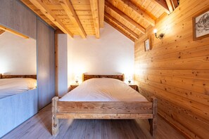 A bedroom with a wooden ceiling, two beds, and a wooden wall with a picture.