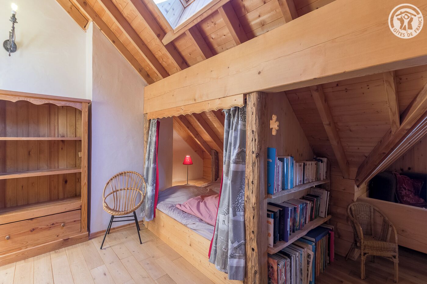A cozy attic bedroom with a bunk bed, a small desk, a chair, and a bookshelf.