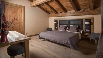 Un dormitorio con techo de madera, una cama con cabecera, mesitas de noche y un escritorio con silla.