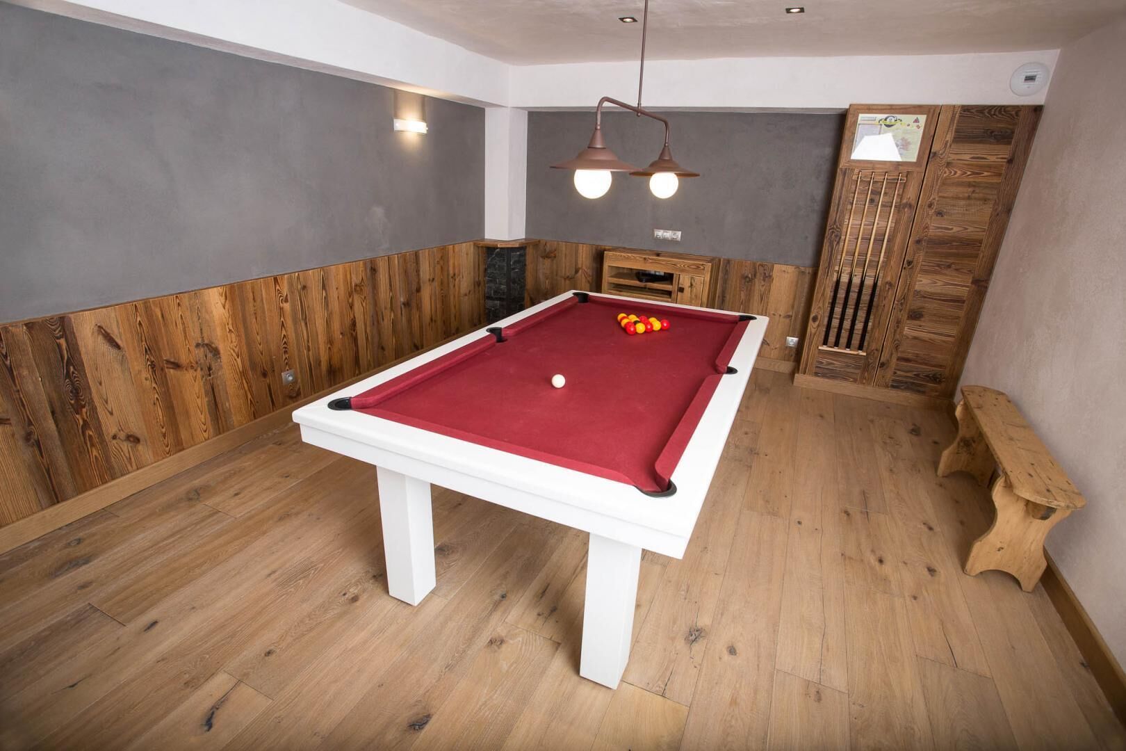 Una mesa de billar en una sala con paneles de madera y un banco de madera.