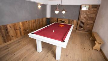 Una mesa de billar en una sala con paneles de madera y un banco de madera.