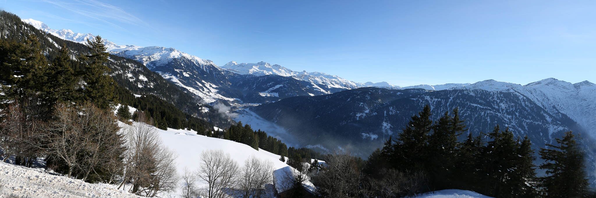 Un paysage montagneux aux sommets enneigés et aux forêts denses.