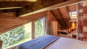 A cozy attic bedroom with a large window, wooden beams, a bed, a desk, and a wardrobe. - LE Chomesi - Hauteluce-les-saisies (HAUTELUCE LES SAISIES)