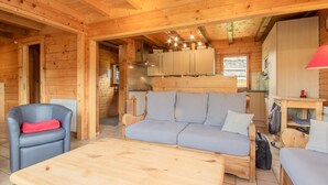 A cozy wooden cabin interior with a sofa, a chair, a table, and a kitchenette. - LE Chomesi - Hauteluce-les-saisies (HAUTELUCE LES SAISIES)