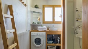 Un baño pequeño con lavadora, lavamanos y ducha.