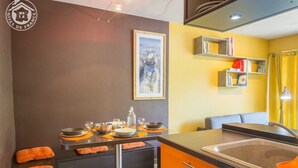 Cocina compacta con comedor, que incluye una isla central, un fregadero y un cuadro en la pared.