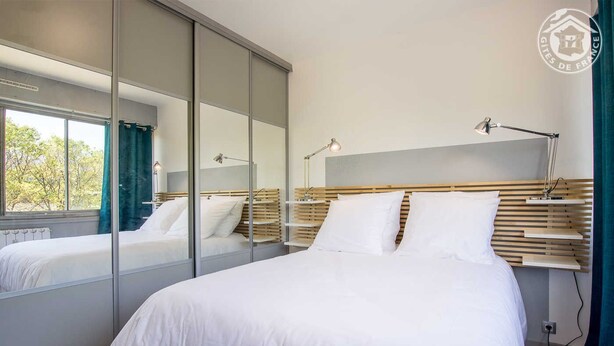 Un dormitorio moderno con una cama grande, un espejo y lámparas de noche.