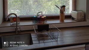 Eine Küche mit Fenster, Spüle, Toaster und einem Metallregal.