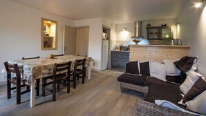 Un espacio habitable compacto con comedor, kitchenette y sofá.