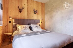Una camera da letto con una testiera in legno, due cuscini a forma di cuore e un letto con una coperta decorata.