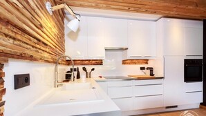 Una cocina moderna con armarios blancos, un panel de madera y un horno empotrado.
