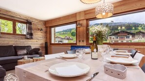 Un interior de madera con zona de comedor, ventanas amplias y vistas al campo.