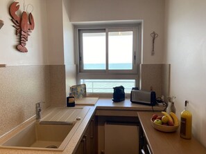 Eine Küche mit einem großen Fenster, einer Spüle, einem Toaster und einer Schüssel mit Obst.