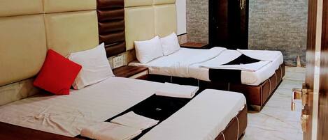 A hotel room with three beds, a wooden headboard, a brick wall, and a ceiling fan.