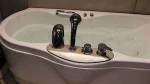 Une baignoire blanche avec un robinet chromé et un bouton de commande.