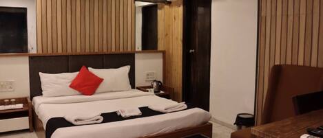 Habitación de hotel con cama, mesita de noche, mesa de centro y escritorio con silla.