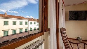 A balcony with a view of buildings, a chair, and a radiator.
