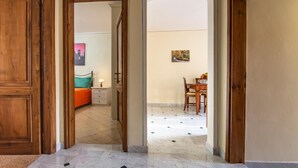 Un couloir avec des portes en bois donnant sur une chambre et un coin repas.