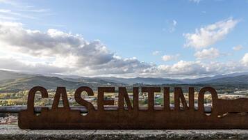 A metal sign with the word "CASENTINO" against a backdrop of mountains and a partly cloudy sky.