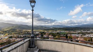Un lampadaire surplombe une ville, avec des bâtiments et des collines en arrière-plan.