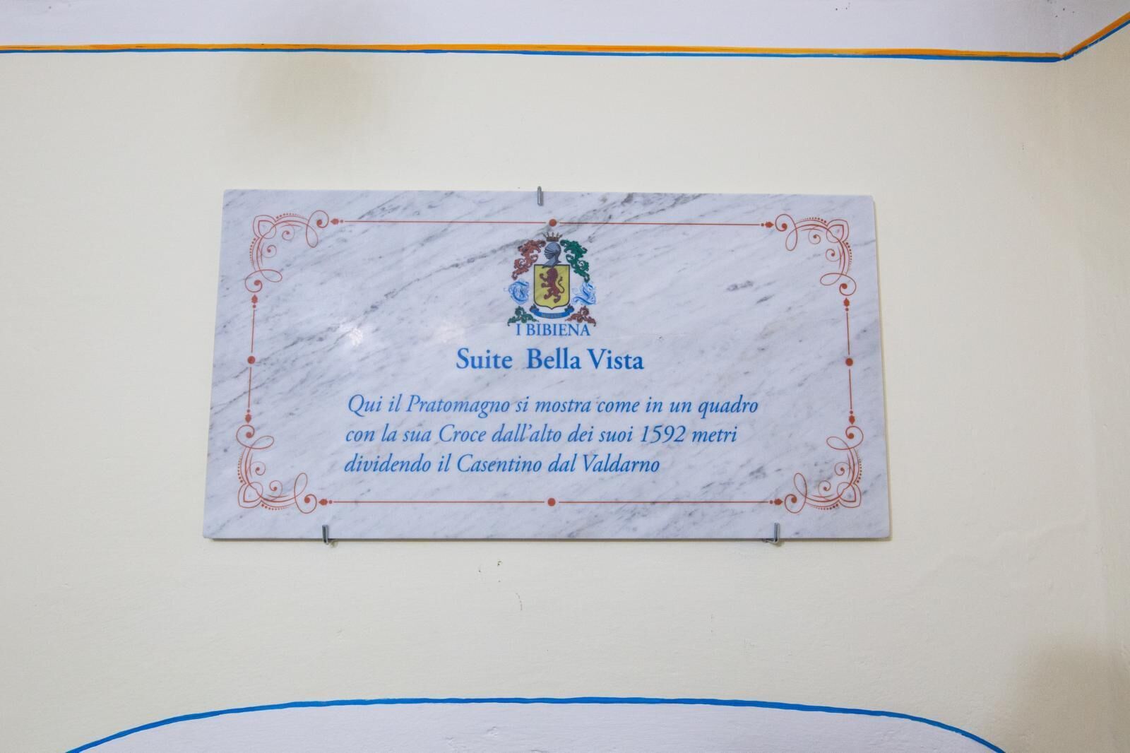 A marble plaque with a coat of arms and text in Italian, mounted on a wall.