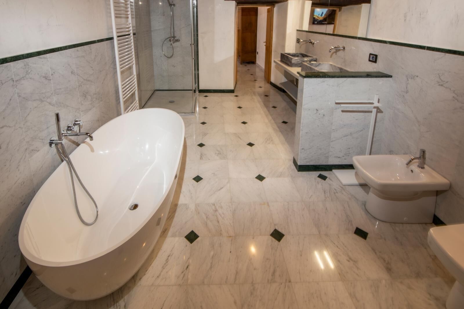 A modern bathroom with a large bathtub, a separate shower area, a bidet, and a vanity with a mirror.