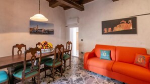 A dining area with a wooden table and chairs, a fruit bowl, and a hanging light fixture. - The Bibiena Suites in the Historic Center (Bibbiena)