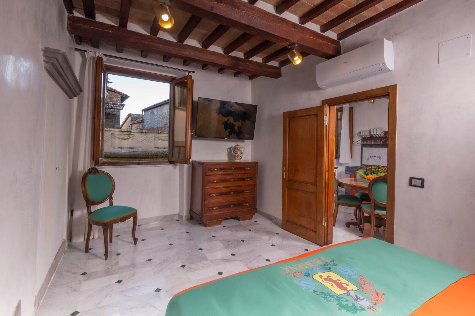 Quarto com cama, cômoda, cadeira, escrivaninha com cadeira, janela e um quadro na parede.