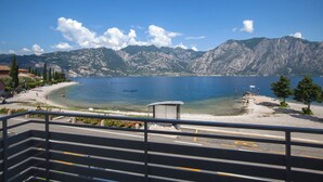 Une vue sur le lac, avec des montagnes en arrière-plan, une plage et un petit pavillon.