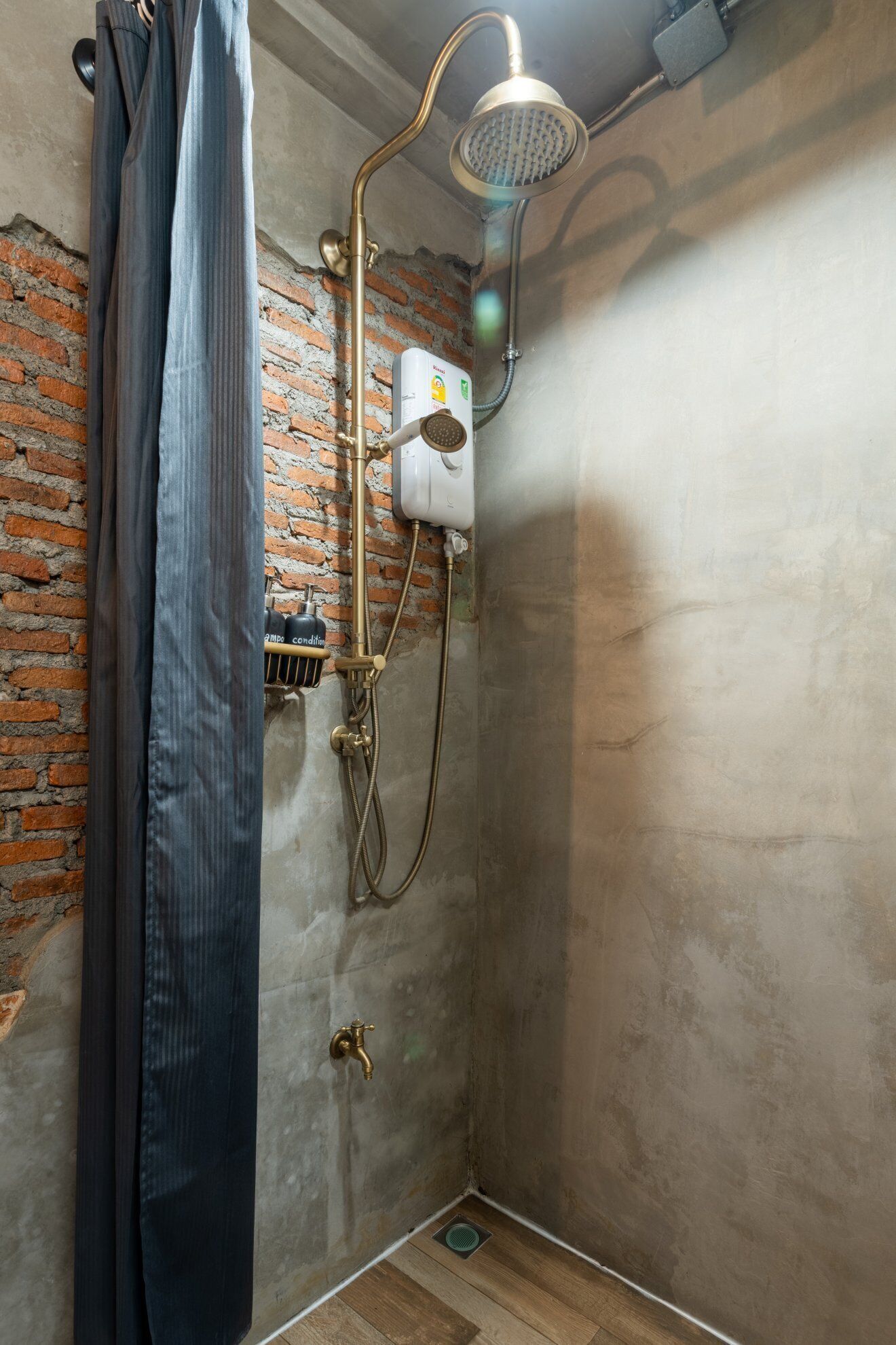 A shower area with a showerhead, a water heater, and a drain.