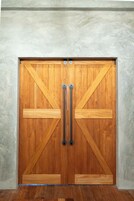 Una puerta doble de madera con tiradores de metal y un diseño de refuerzo en forma de cruz.