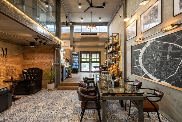 A spacious reception area with a large map, leather seating, and a coffee machine. - House of Machine Boutique Hotel  (Bangkok)