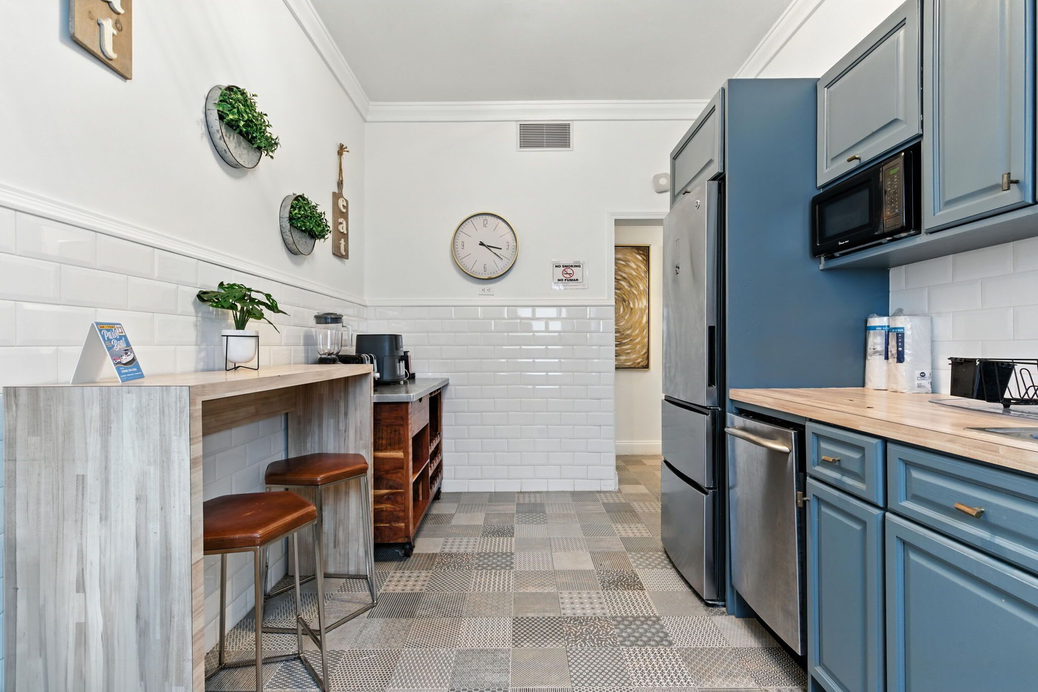 Une cuisine moderne avec des carreaux de céramique blancs disposés en motif métro, une horloge et un four à micro-ondes.