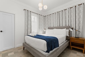 Ein ordentlich eingerichtetes Schlafzimmer mit Bett, Nachttisch und Lampe.