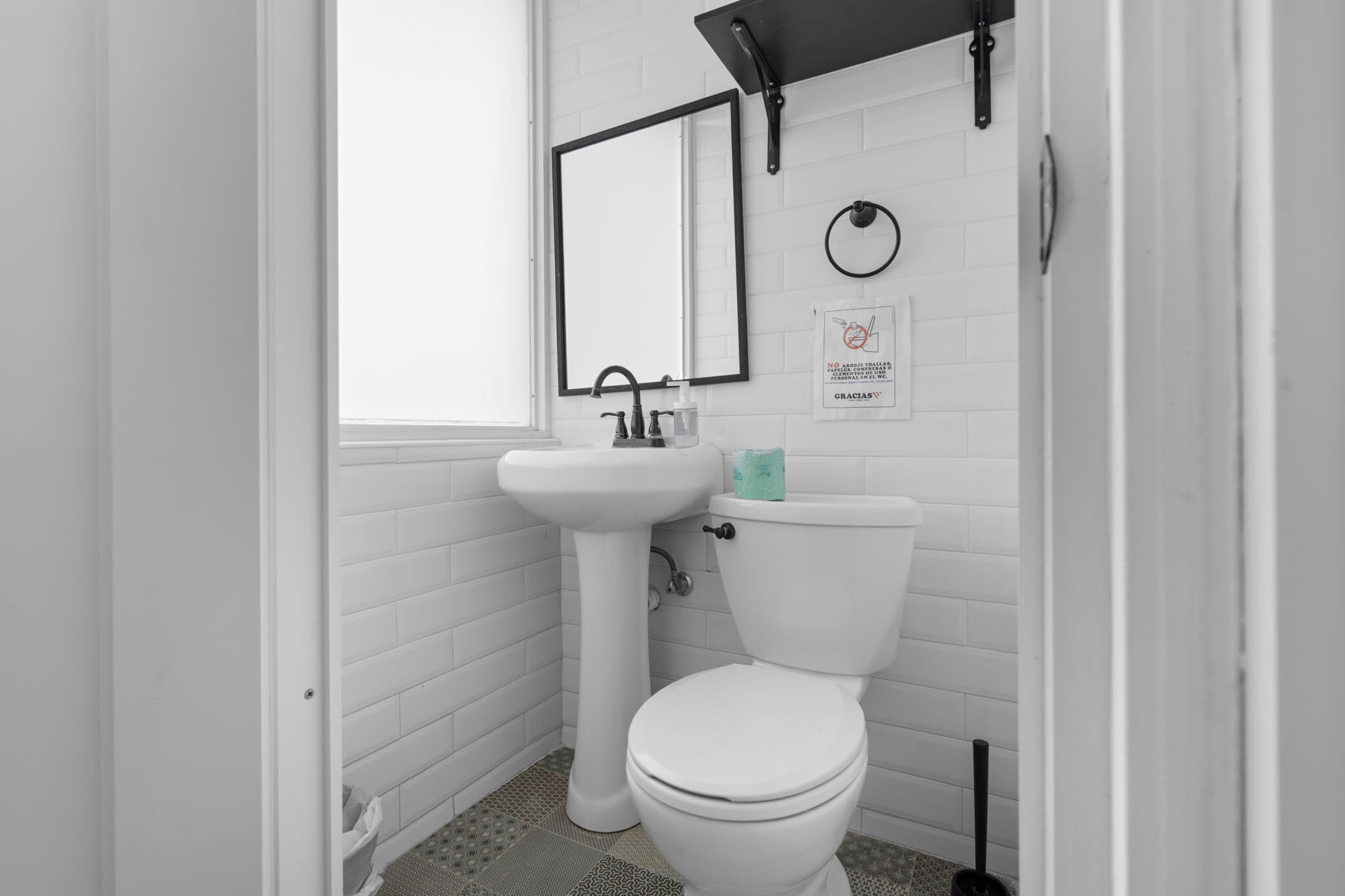 Un bagno piccolo e bianco con un lavabo su piedistallo, un water e uno specchio.